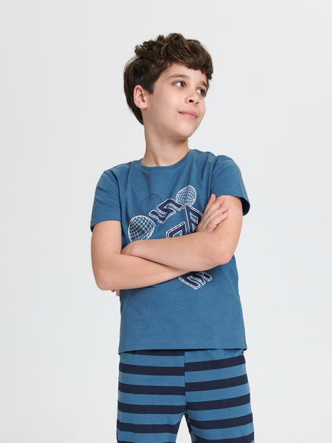 Child wearing a blue t-shirt with graphic design and striped pants on a white background