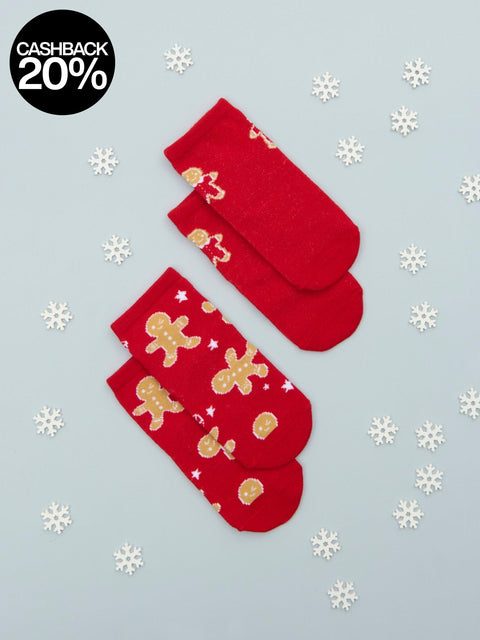 Red socks with gingerbread men pattern on a light blue background with snowflakes and cashback offer.