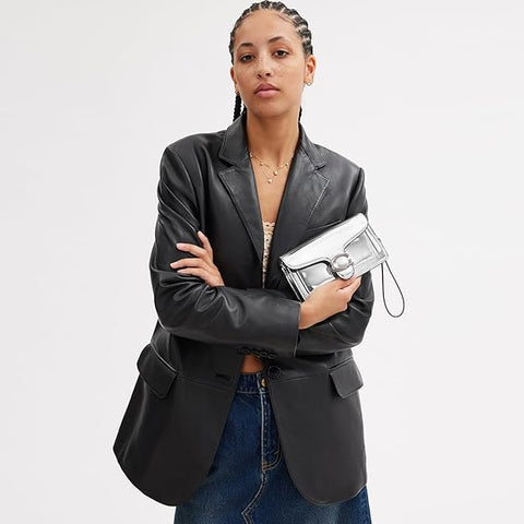 Woman holding a silver clutch against a plain background