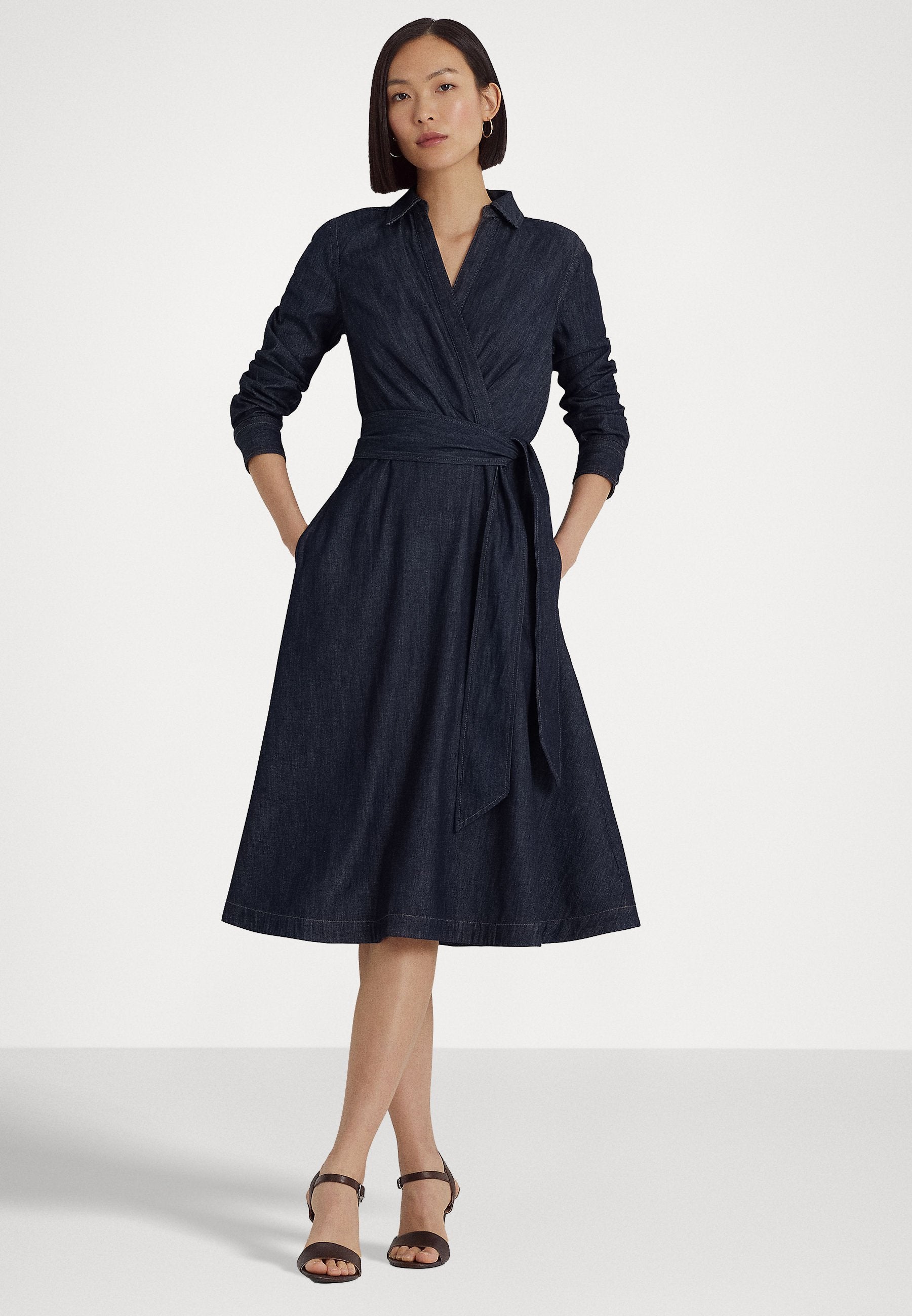 Woman wearing a navy blue dress with a belt on a white background