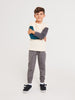 Child wearing a white shirt with gray sleeves, gray pants, and black shoes on a white background