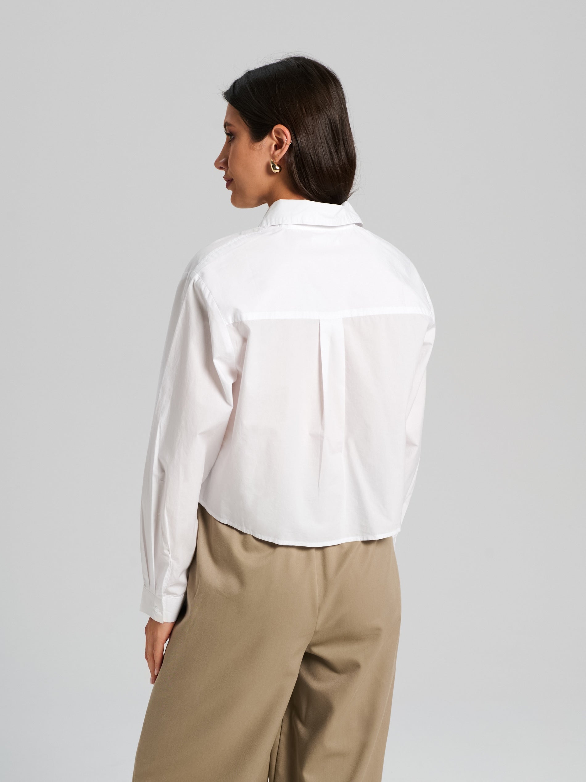 Person wearing a white shirt and beige pants on a gray background