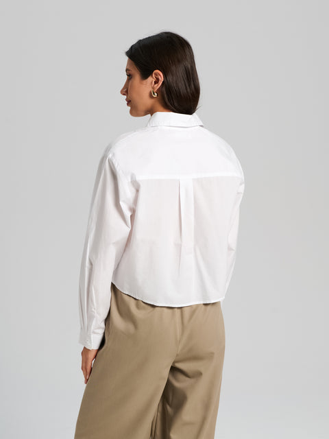 Person wearing a white shirt and beige pants on a gray background