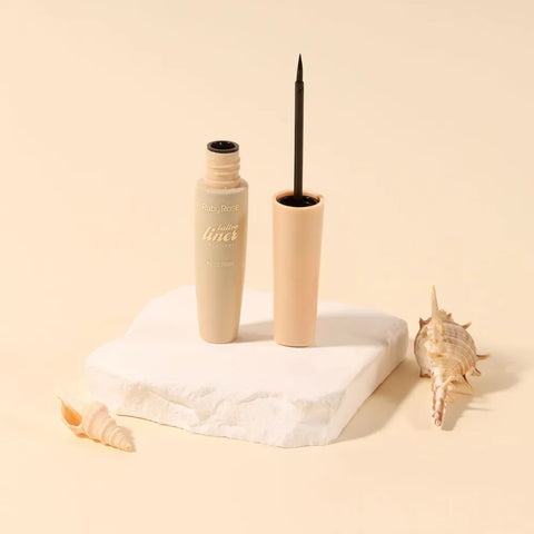 Beige mascara with black wand on a white marble block against a beige background