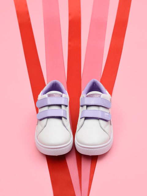 White sneakers with purple straps on a pink and red striped background