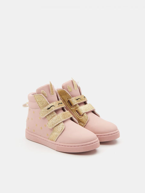 Pink high-top sneakers with gold glittery straps on a light pink background