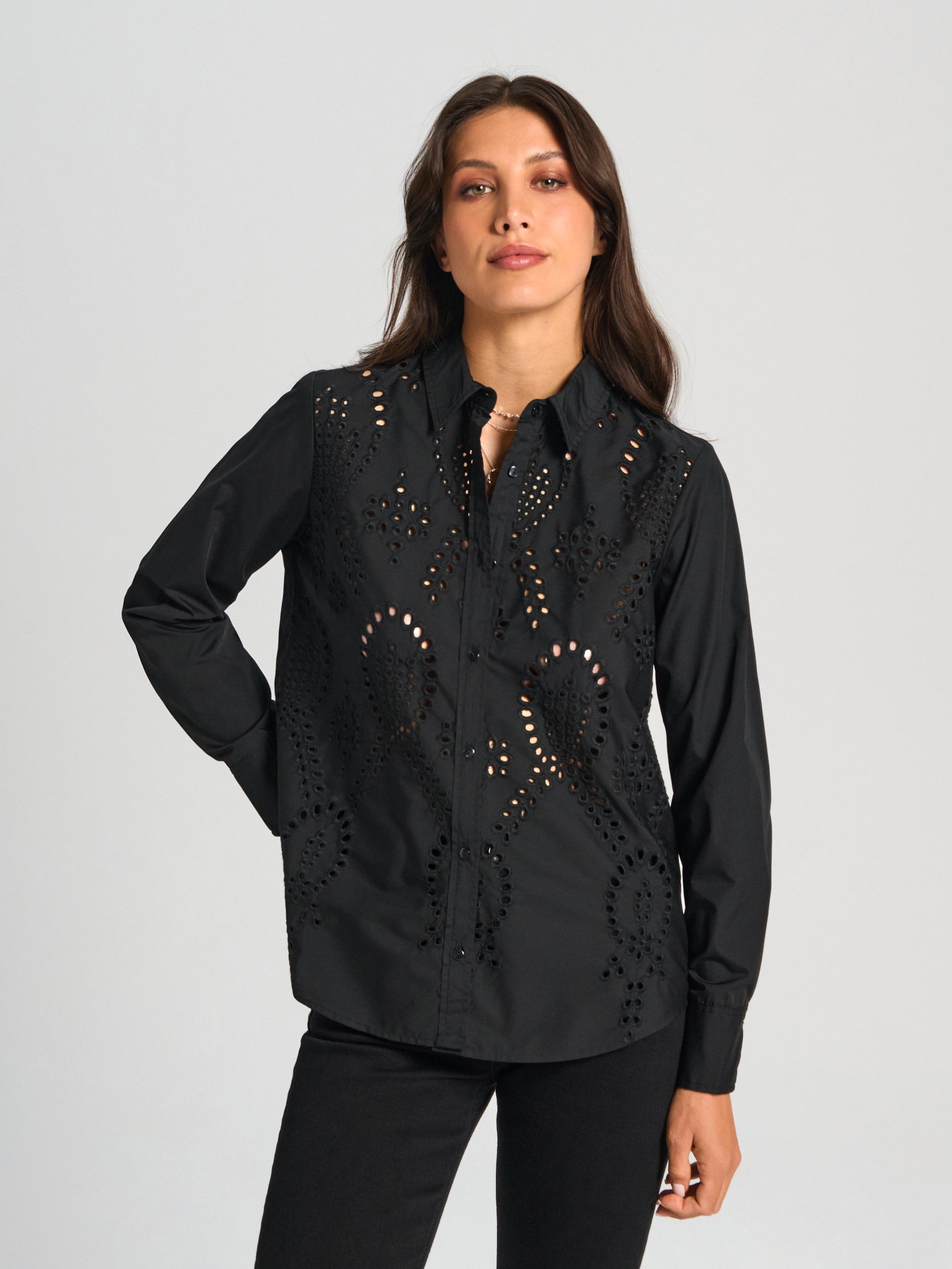 Woman wearing a black shirt with cut-out designs on a gray background