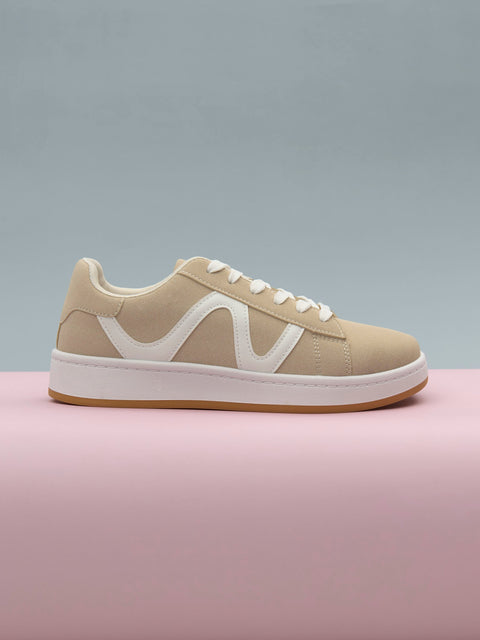 Beige sneaker with white accents on a pink platform against a gray background