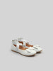 White shoes with bow details on a light gray background