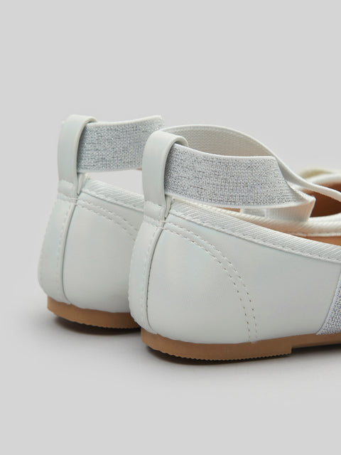 White flat shoes with a brown sole on a light gray background
