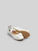 White children's shoes with a bow on a light gray background
