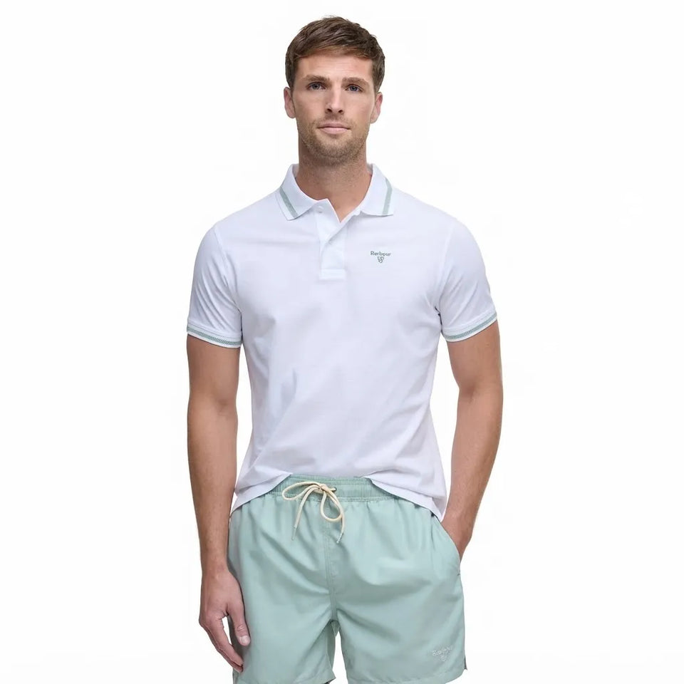 A man wearing a white short-sleeve polo shirt with light blue-green trim on the collar and sleeve cuffs, paired with mint green drawstring shorts, against a plain white background.
