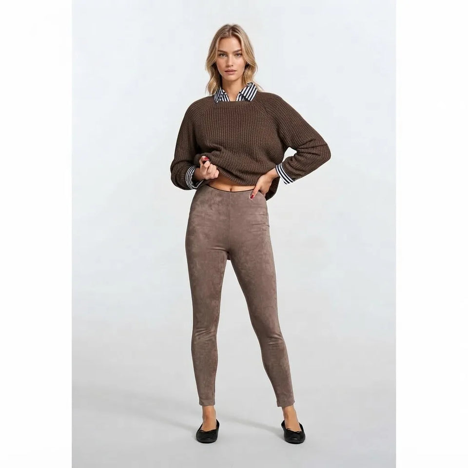 A woman modeling a brown ribbed knit sweater with a black and white striped collar, paired with brown leggings and black flats, against a light gray studio background.