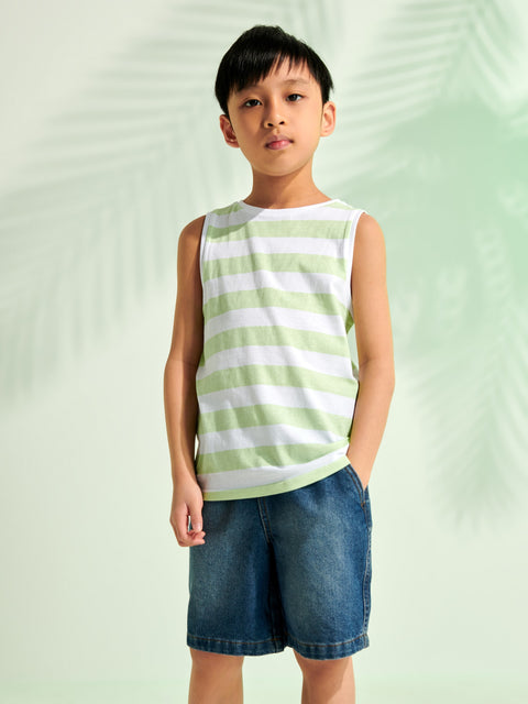 Child wearing a green and white striped tank top and blue shorts on a light green background