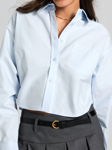 Light blue shirt worn by a person with gray pleated pants and a black belt.