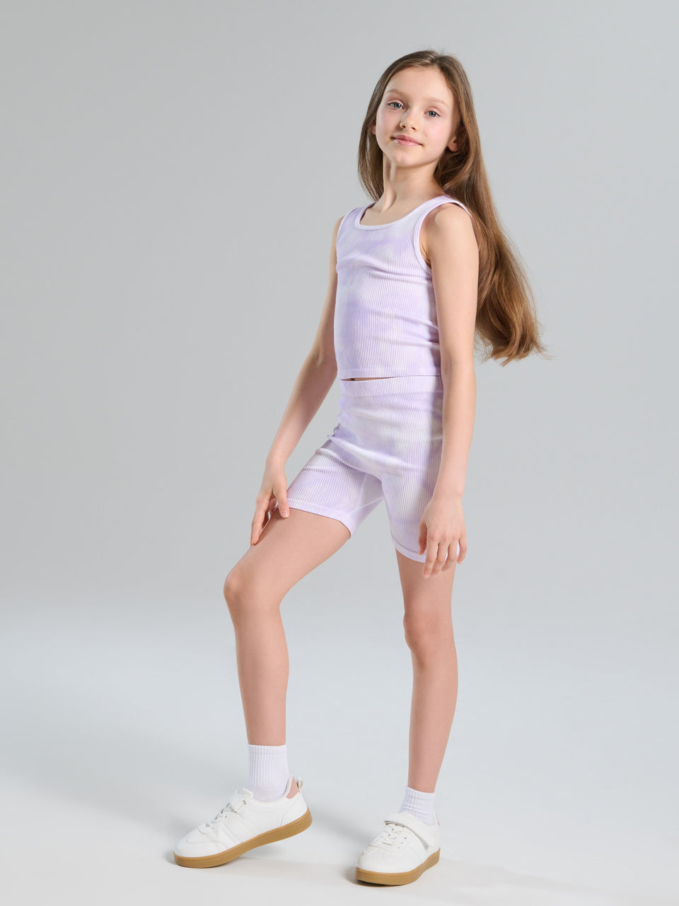 Young girl wearing a light purple sleeveless top and shorts set on a gray background