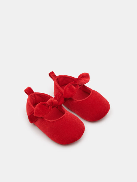 Red baby shoes with bows on a white background
