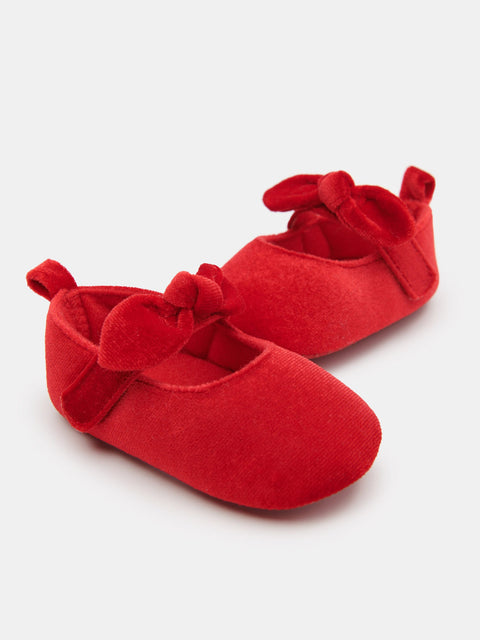 Red baby shoes with bows on a white background