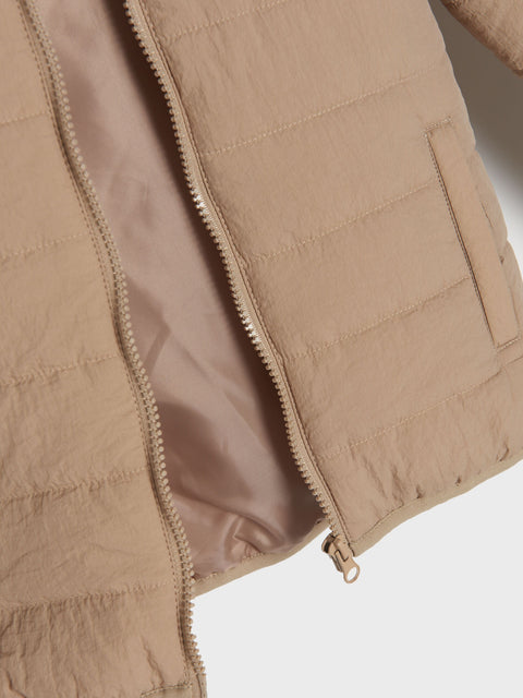 Close-up of a beige quilted jacket with zipper on a light gray background
