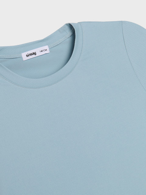 Light blue t-shirt with a visible brand label on a light gray background