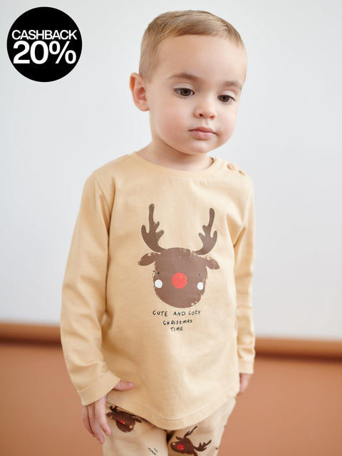 Child wearing a beige long-sleeve shirt with a reindeer graphic and text.