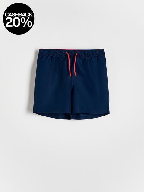 Navy swim shorts with a red drawstring on a light gray background