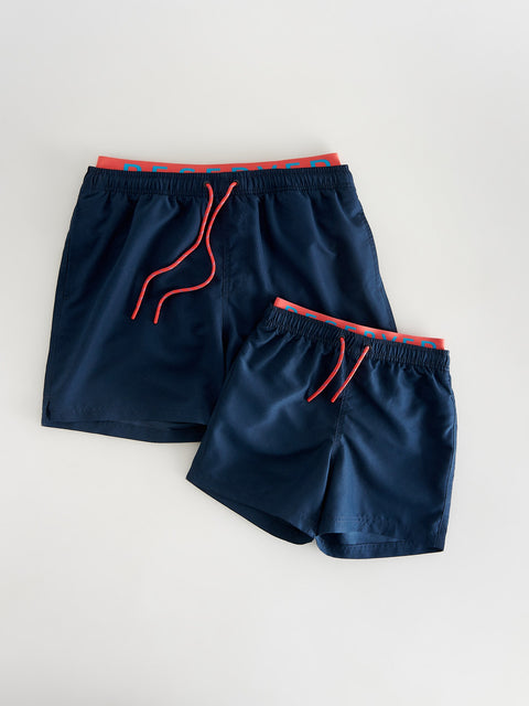 Two pairs of navy shorts with red drawstrings on a light gray background
