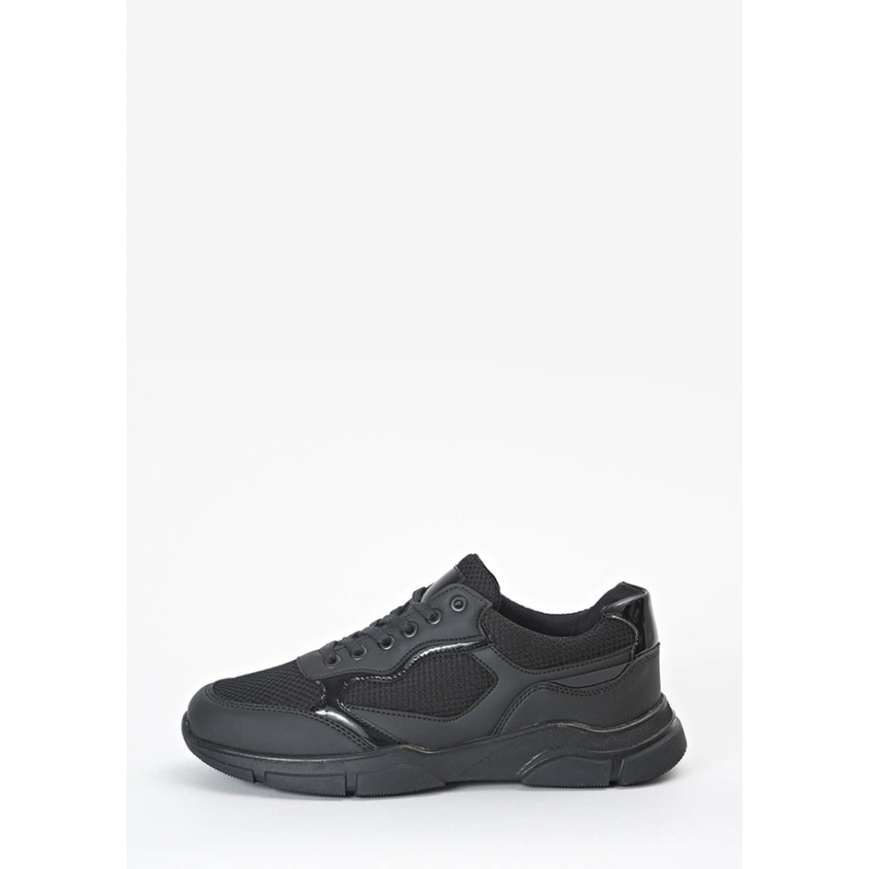 A black low-top sneaker with a chunky, sculpted sole, mesh panels, and synthetic overlays, shown from a side profile on a light gray background.