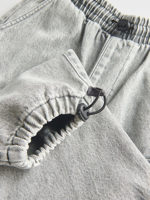 Close-up of a gray denim fabric with a button and zipper detail.
