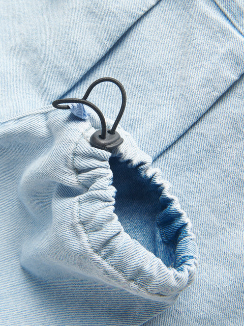 Close-up of a blue denim jacket with a black button and tag.