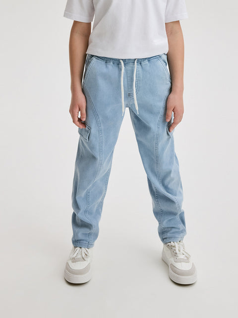 Person wearing light blue jeans and white sneakers on a white background