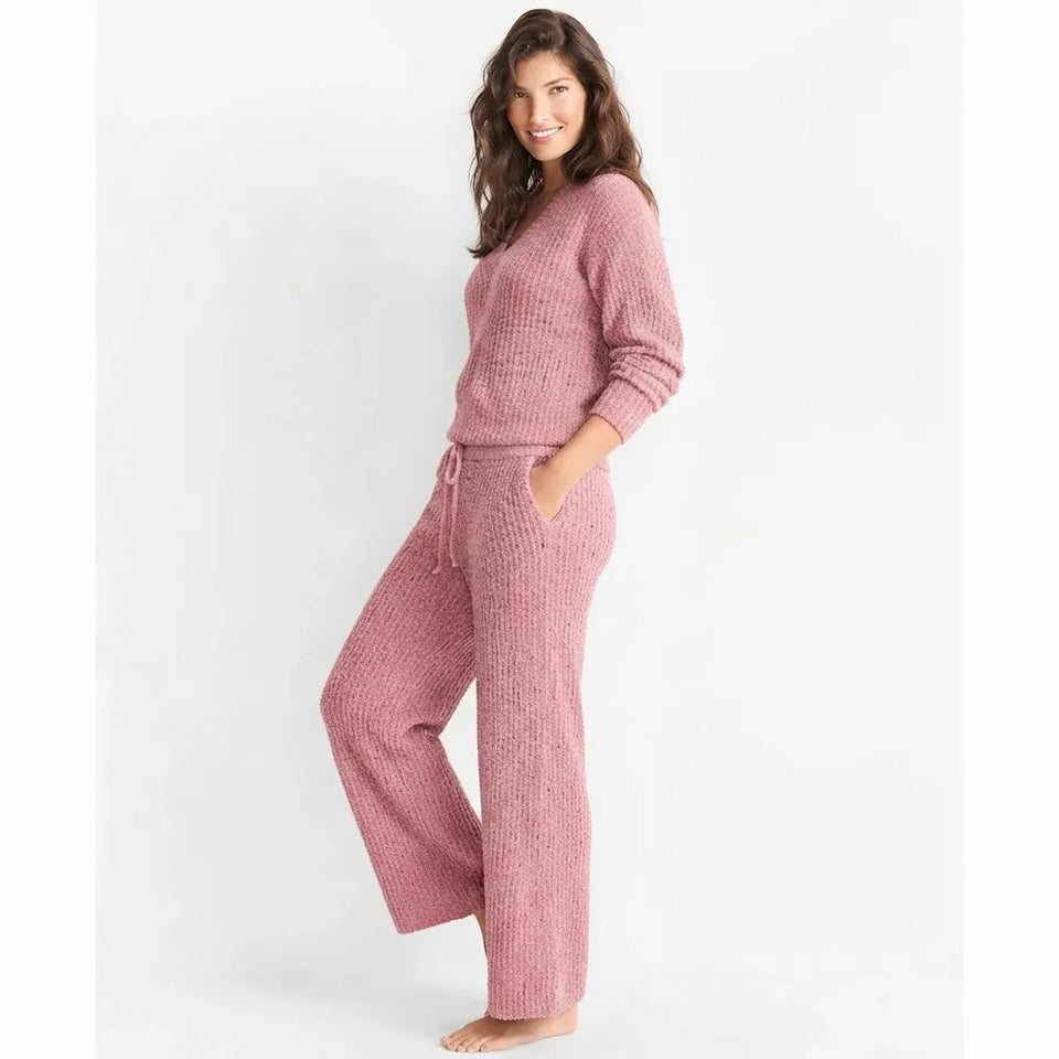 A woman modeling a matching knit lounge set consisting of a long-sleeve top and wide-leg pants in a dusty rose pink color, set against a plain white studio background.