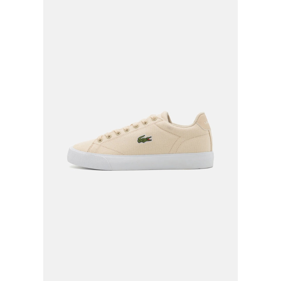 A single Lacoste low-top sneaker in beige canvas with a white rubber sole and the signature green crocodile logo on the side, shown against a light gray background.