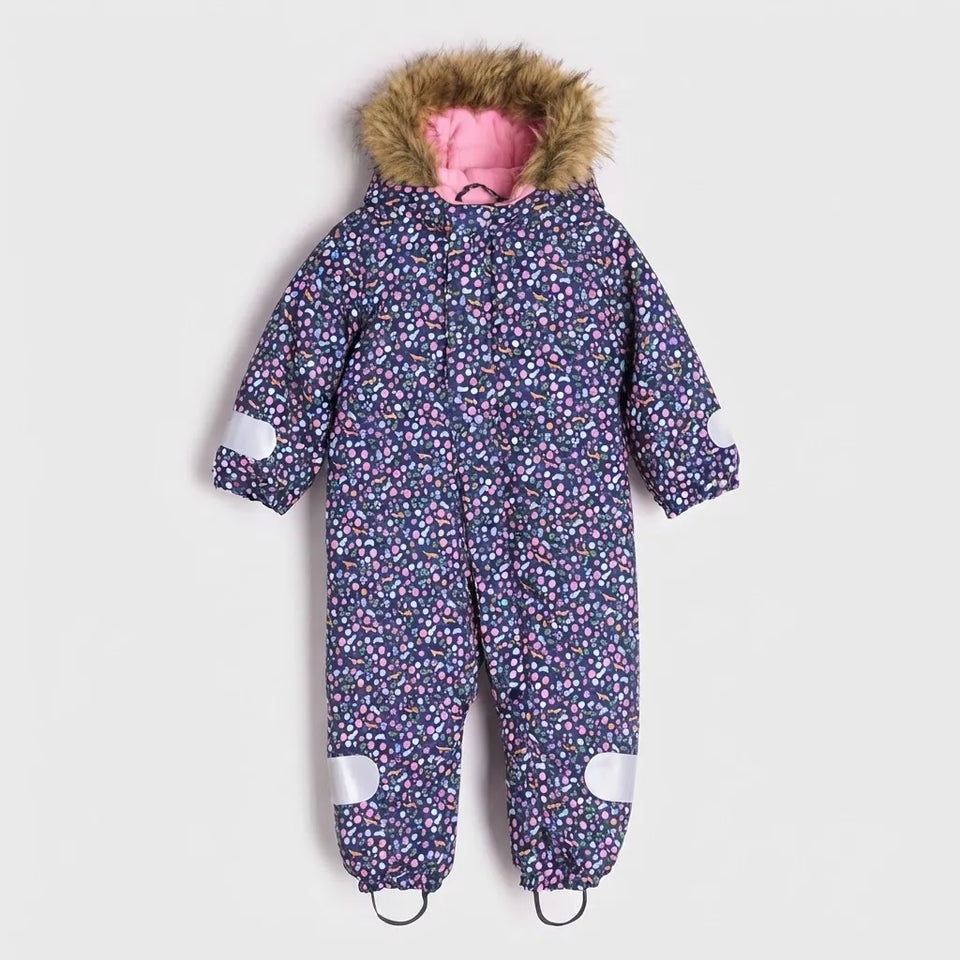A children's full-body snowsuit with a dark blue and pink floral pattern, featuring a brown faux-fur trimmed hood with a pink lining, white elbow patches, and white knee patches.