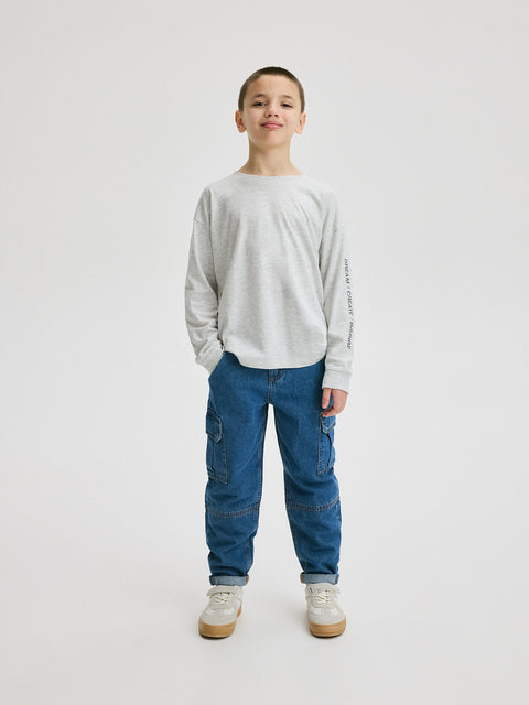 Child wearing a gray sweater and blue jeans on a white background