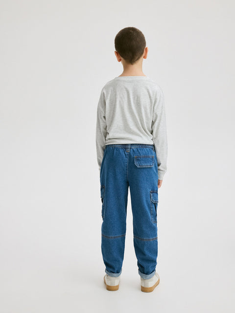 Person wearing blue cargo pants and a light gray sweater on a white background