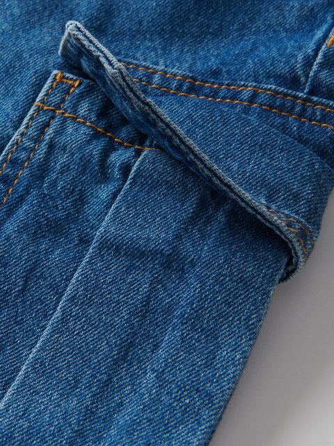 Close-up of blue denim fabric with stitching detail on a gray background