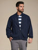 Man wearing a navy bomber jacket over a striped shirt on a beige background