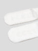 White slippers with fur trim on a light gray background