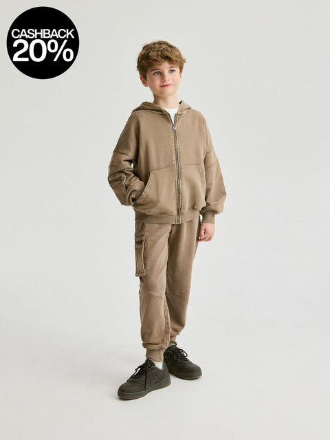 Child wearing a brown tracksuit on a white background