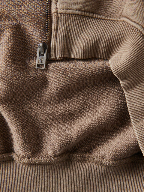 Close-up of a brown fleece jacket with a brand logo on the chest pocket.