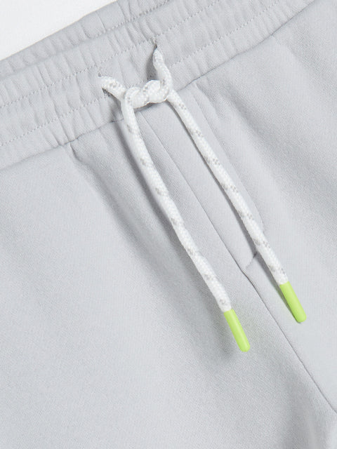 Gray sweatpants with a white drawstring featuring green accents on a light gray background