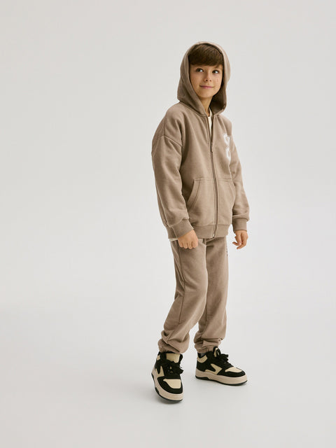 Child wearing a beige tracksuit with a hood on a white background