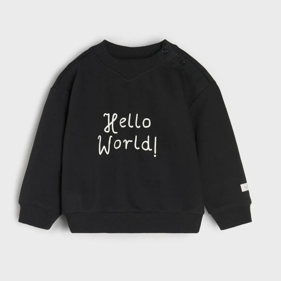 A black long-sleeve crewneck sweatshirt for toddlers, featuring the words 'Hello World!' printed in white script across the chest, displayed on a light gray background.