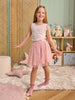 Young girl in a pink dress standing in a room with toys and decor