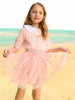 Young girl in a pink dress with a white collar standing on a beach.