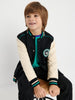 Child wearing a black and white varsity jacket with a logo on a white background
