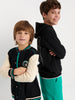 Two children wearing black hoodies with different color accents on a white background