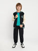 Child wearing a varsity jacket, teal shirt, black pants, and sneakers on a white background