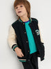 Child wearing a black varsity jacket with white sleeves and a teal shirt against a light gray background